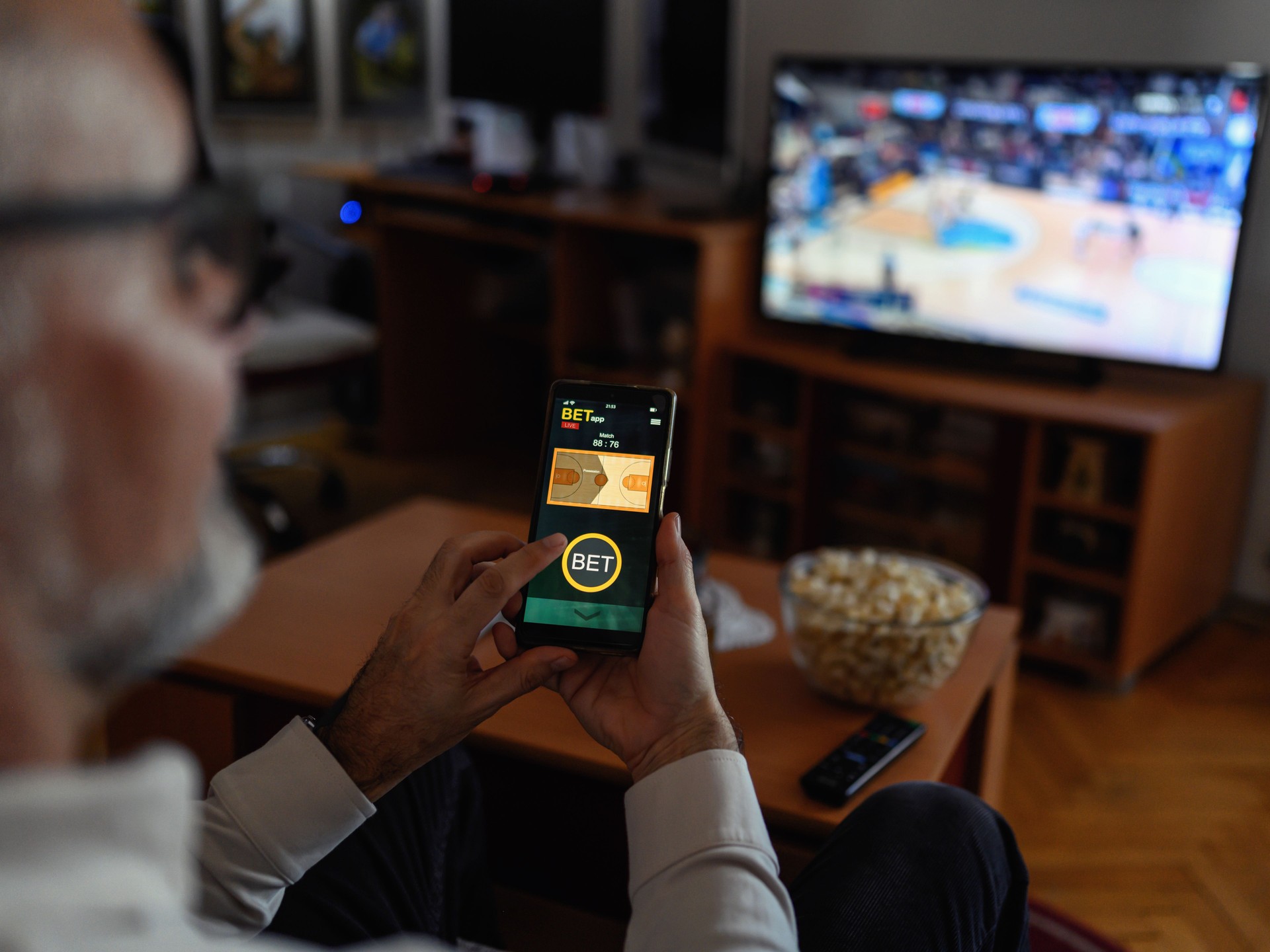 Mature men using smart phone for sports betting.